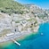 A beach with designated swimming areas and lounge chairs below a series of terraced gardens on a rocky cliff